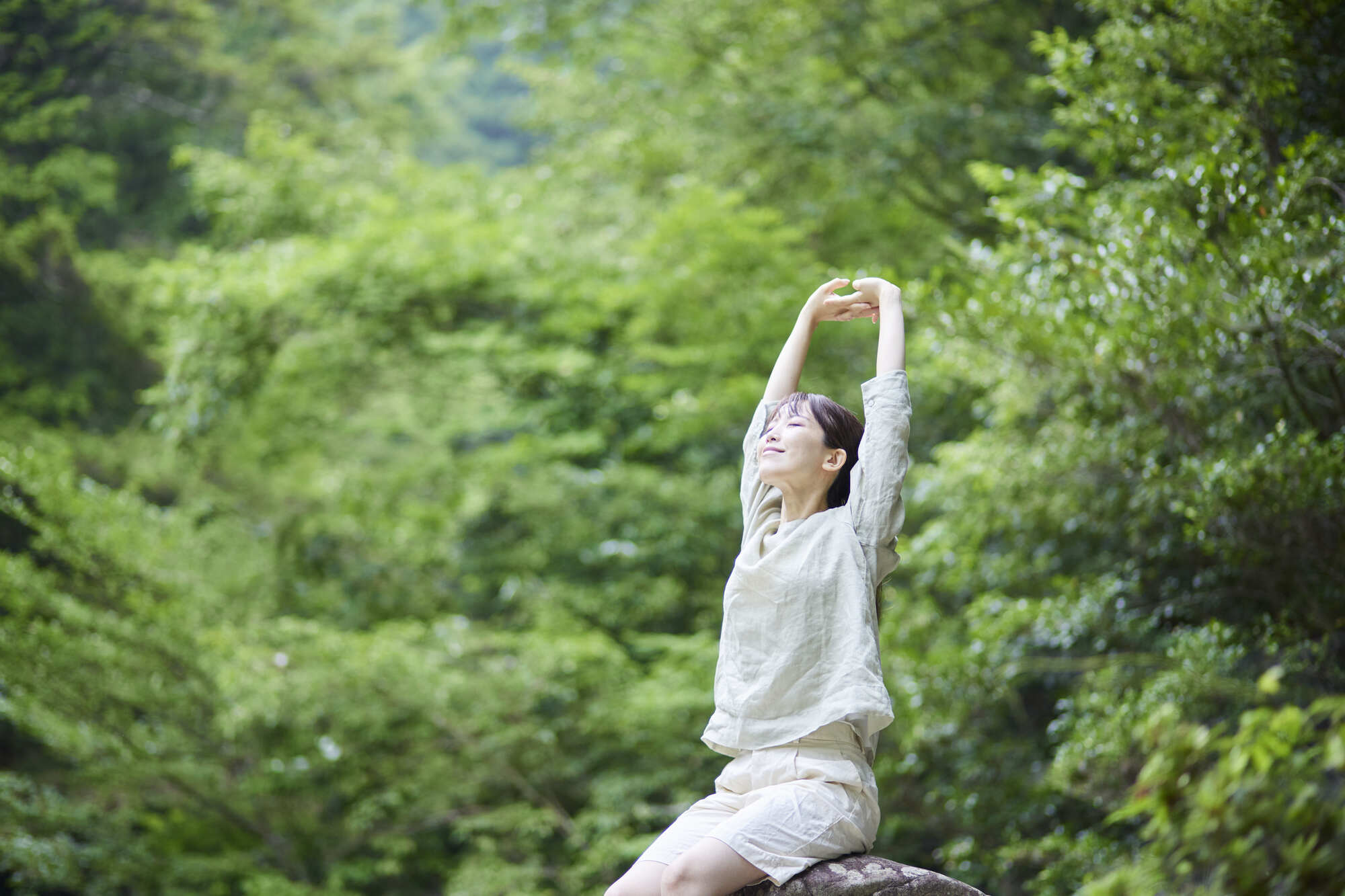 緑の中で伸びをする女性